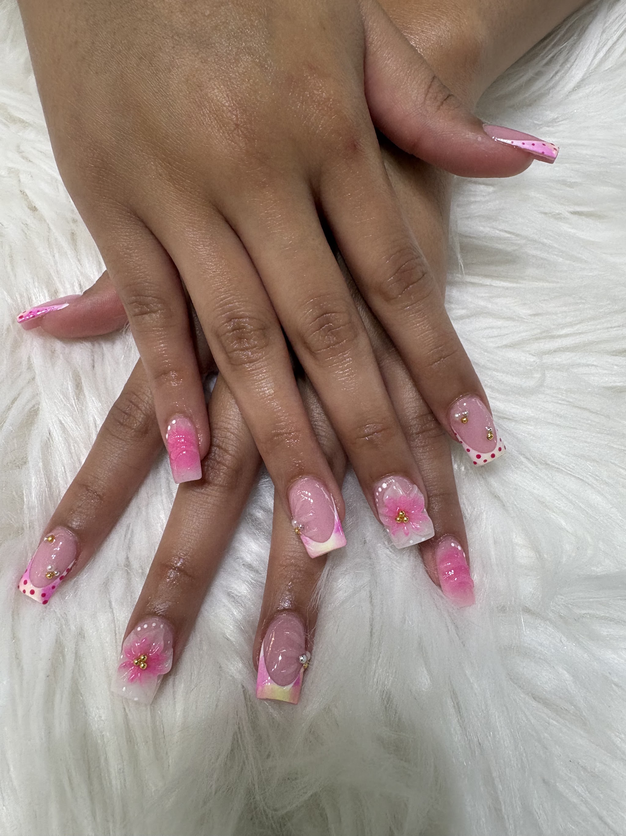 Short pink nails with flowers and polka dot tips on a white fur background
